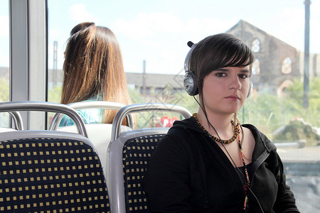 年轻女士在电车上监听她的耳机图片