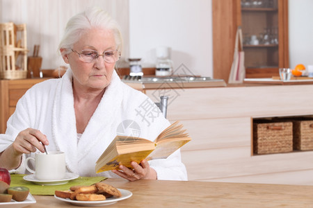路由老年妇女在早餐时阅读背景