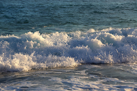 海浪和白泡沫在岸的夜晚阳光下图片