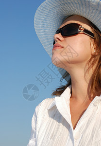戴眼镜和帽子的女人在天空背景上穿白衣服的成年女孩图片