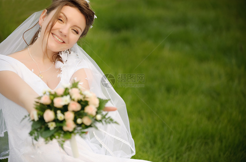 在草坪上的新娘穿着婚纱的年轻女孩图片
