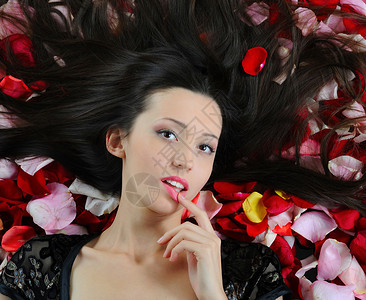 红玫瑰花瓣中美丽的褐发女肖像图片