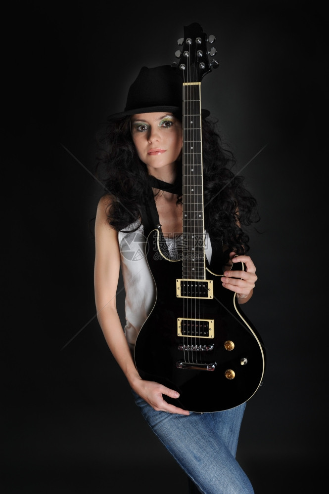 一个美丽的长头发女孩的肖像手拿着吉他背黑色景图片