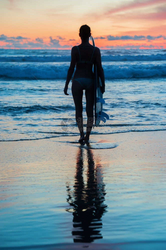 美丽的年轻女子冲浪在海滩上挂板子图片
