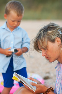 妈读书在晚上沙海岸和附近的小男孩图片