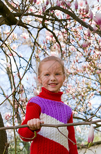 快乐的小女孩肖像在盛开的木兰花树附近图片