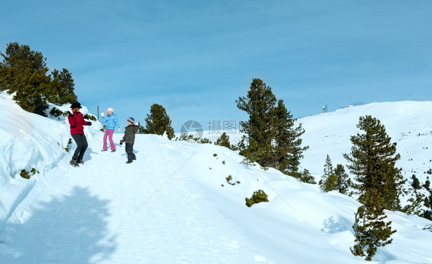 家庭有两个孩子的母亲在冬季山坡上玩雪球游戏图片