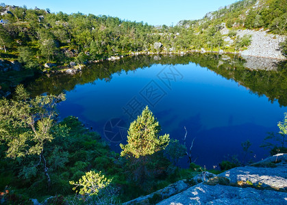 挪威深蓝色小山丘湖有岩石海岸图片