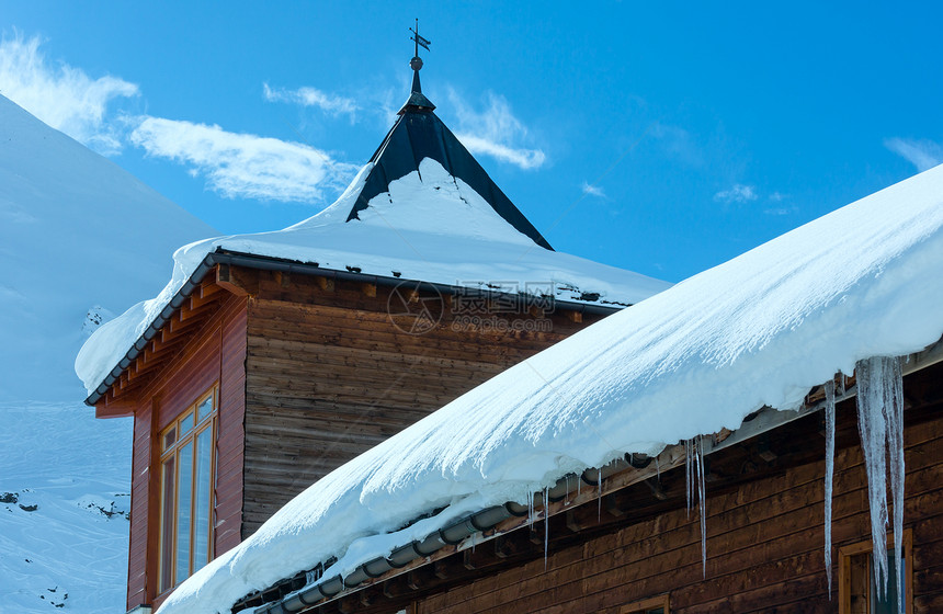 冬季山坡上的木屋顶有雪和冰块图片