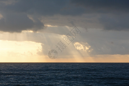 海景和太阳光束穿透灰云图片