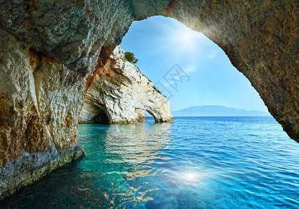 岩石洞蓝洞中的阳光从船拱门Zakynthos希腊斯基纳里角背景