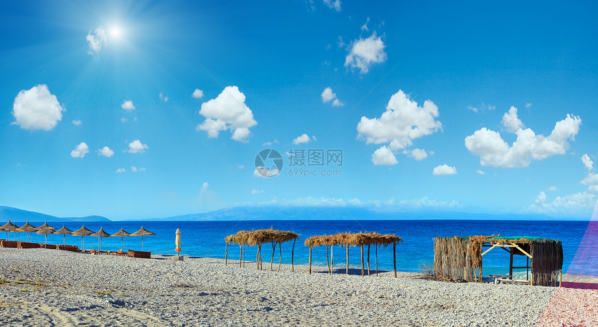 夏晨沙滩有日晒床树冠和白石块阿尔巴尼亚伯什蓝天有云和阳光三针缝全景图片