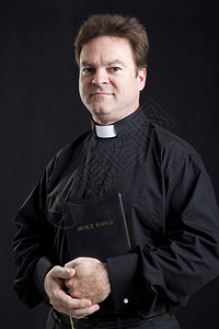 持有圣经的牧师肖像黑色背景图片