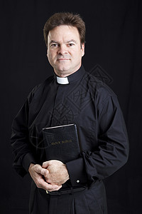 一位持圣经的天主教神父肖像黑色背景神圣的高清图片素材