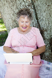 年长妇女喜欢在户外使用网本电脑图片