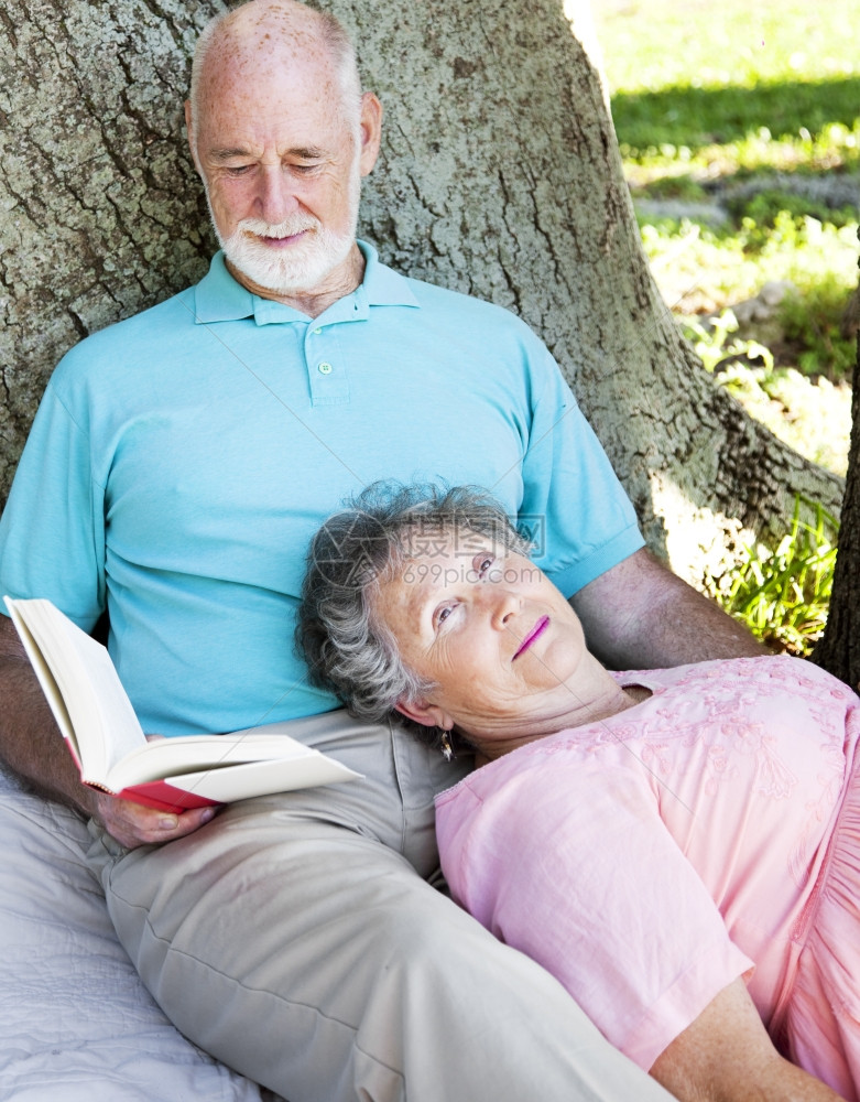 年长者对妻子念书时他们放松在野餐毯子上图片