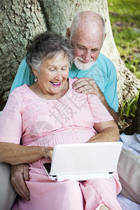 老年夫妇在公园里用网书电脑玩得很开心图片