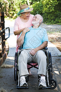 残疾老年男子坐在轮椅上其爱妻照顾他背景图片