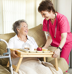 养老院的退休年妇女从护理士那里得到午餐图片