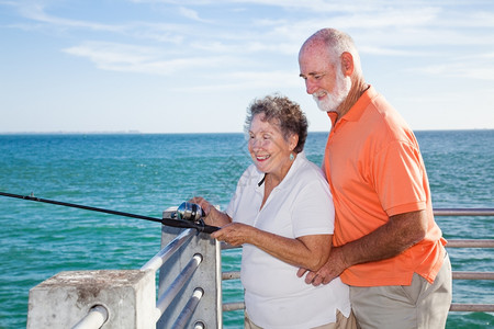 退休的老年夫妇享受在佛罗里达码头一起捕鱼的图片