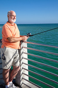 英俊的老年男子享受花他的退休钓鱼图片