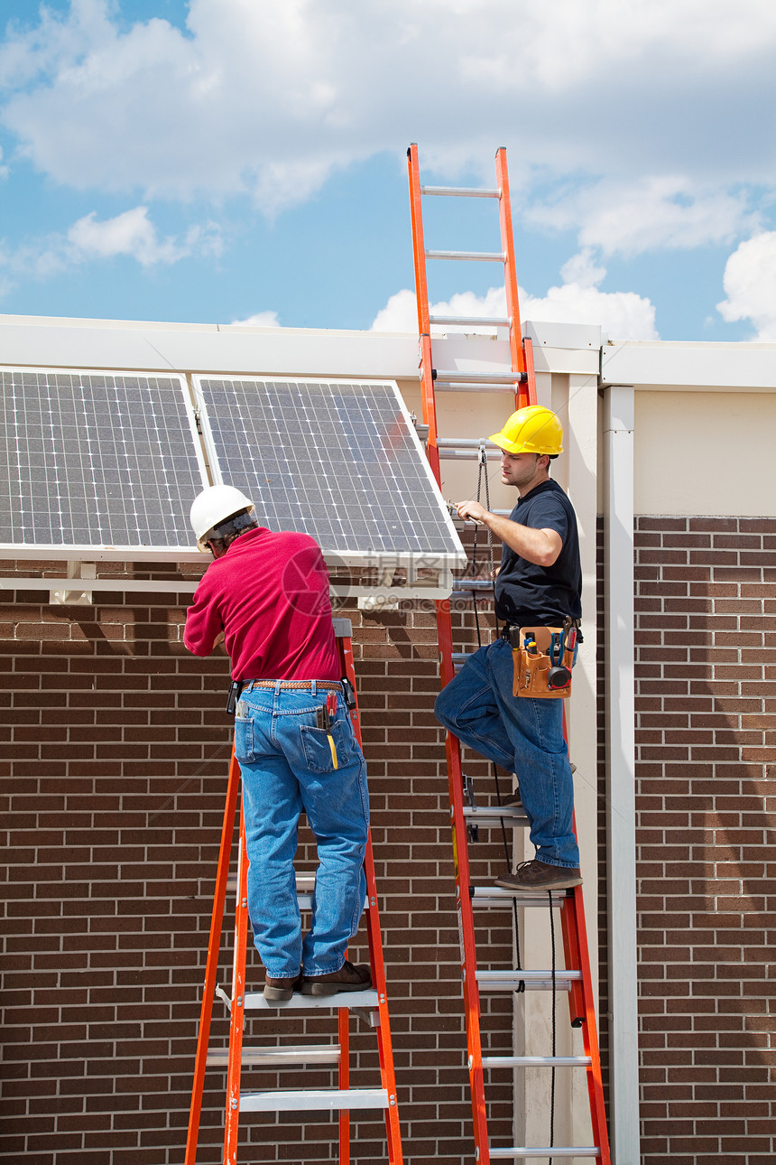 两个工人在一栋楼的侧面安装太阳能电池板垂直与文字空间图片