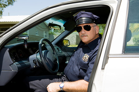 英俊的成熟警官在值班时坐他的警车里图片