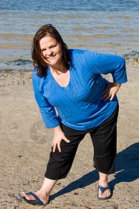 加上在海滩伸展的体型女作为健身计划的一部分图片