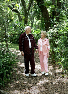 一个有吸引力的老夫妇手牵在公园里漫步高清图片