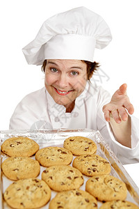 漂亮的厨师给你提供一盘新鲜烤巧克力饼干白的孤立无援图片