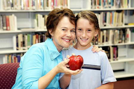 一个可爱的学校男孩给他的老师一个苹果背景图片