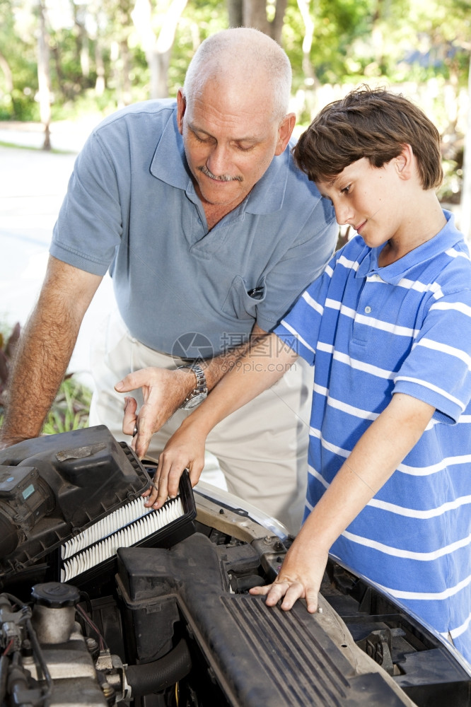 男孩帮助父亲换车引擎的空气过滤器图片