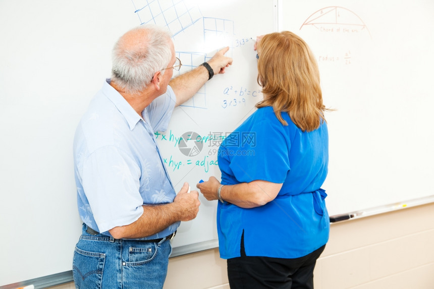成人教育学生在老师的帮助下在董事会上做数学方程式工作图片