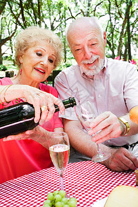 年长夫妇在浪漫野餐上妻子在倒香槟背景图片