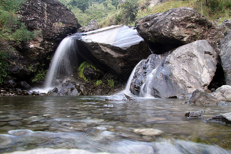 山河中的小瀑布和大石块背景图片