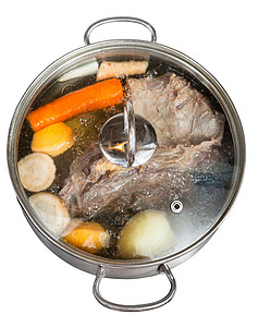 白底绝缘的钢锅里牛肉汤和调味蔬菜图片