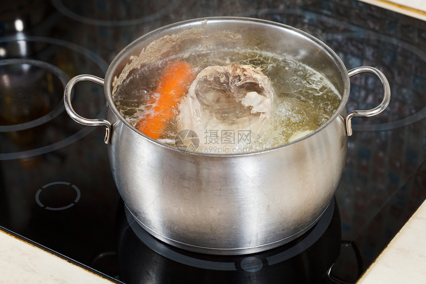 用玻璃陶瓷锅炉在钢中调制蔬菜煮鸡汤图片