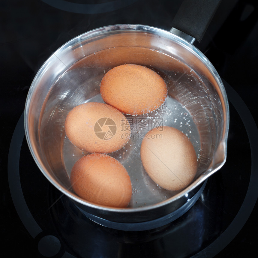 厨房电炉上金属锅中煮鸡蛋图片