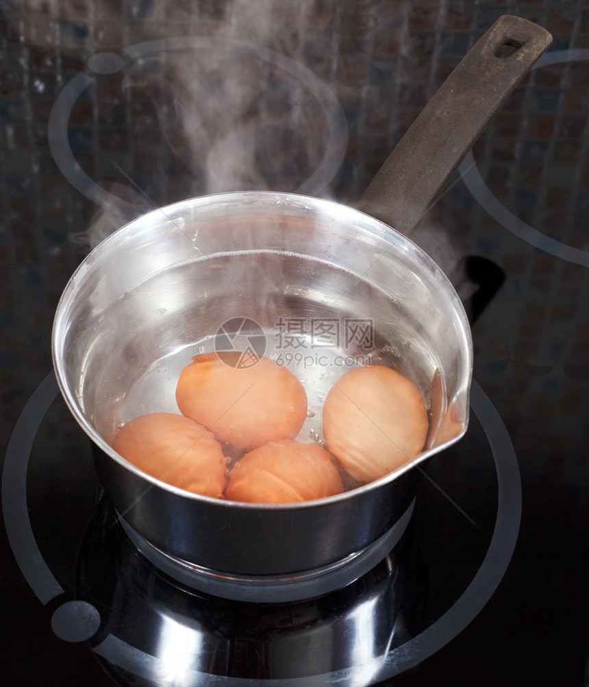 厨房电炉的金属锅中煮鸡蛋图片