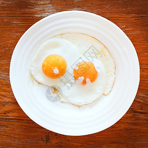 白盘木制桌上有两个煎蛋背景图片