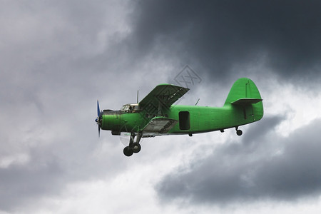 一架绿色飞机在黑暗灰色天空飞过图片