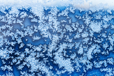 寒冷的冬季夜晚窗户上的蓝色雪花和霜冻模式图片