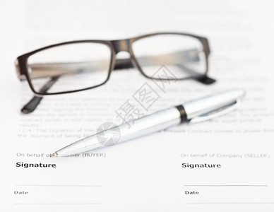 销售合同签字页上的银笔和眼镜图片