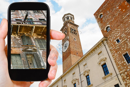 手机外观旅行概念游客用智能手机拍摄意大利维罗纳市中心旧房子的破面孔背景