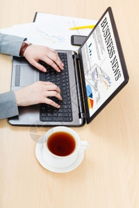 商业工作流程商人在办公桌上从笔记本电脑读到商业新闻图片