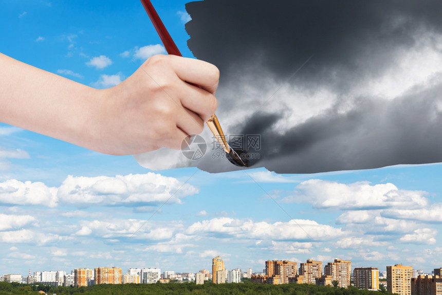 自然概念季节和天气变化手持油漆刷在阳光横扫的城市上暴风云图片