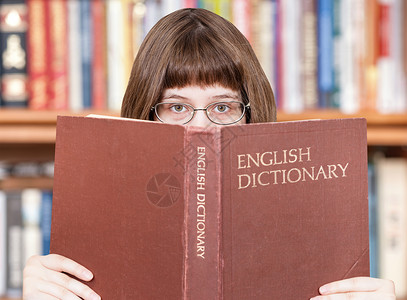 有眼镜的女孩看英语词典书本和背景架背景图片
