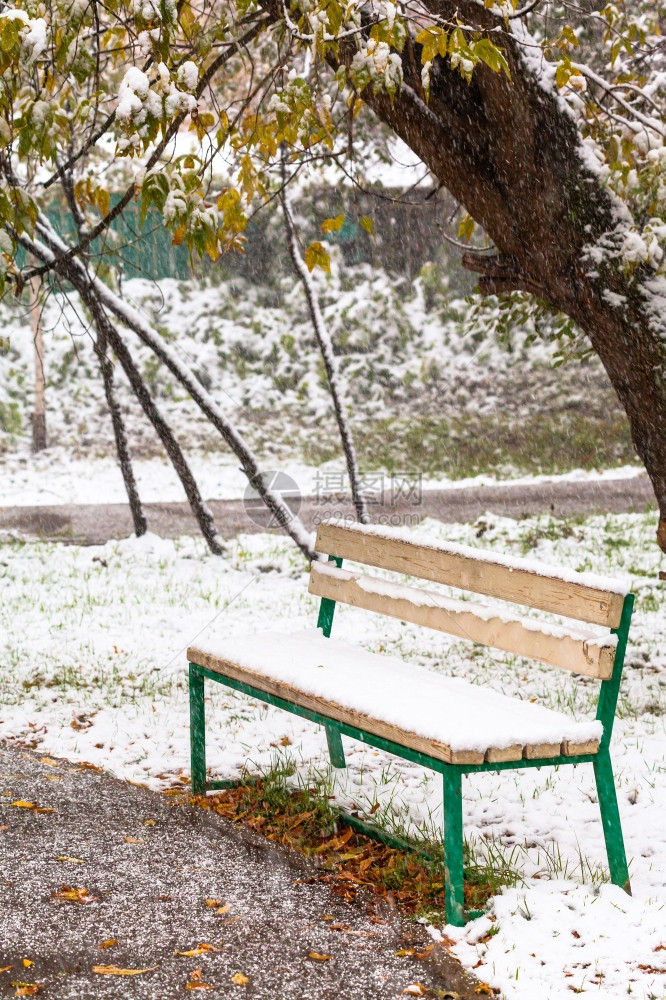 秋天在城市公园第一次下雪和空板凳图片