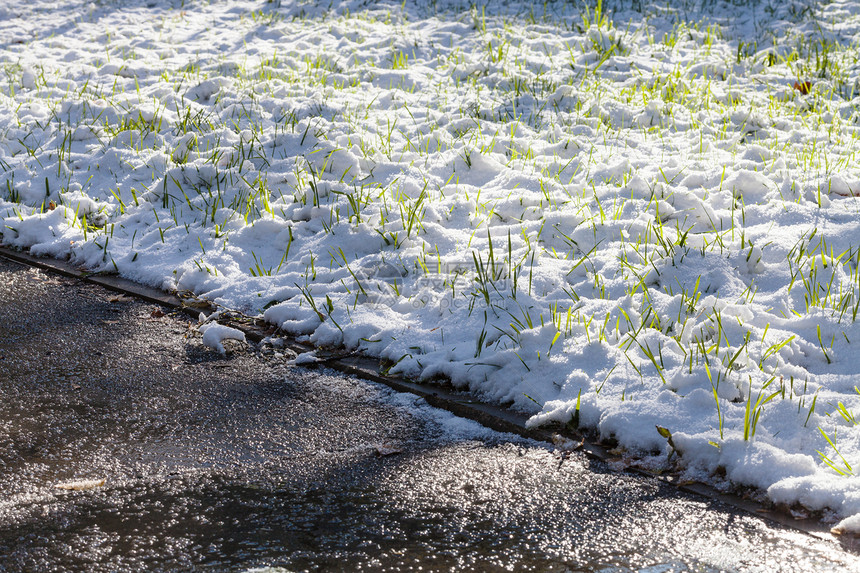 秋天在城市公园绿草地上第一次下雪图片