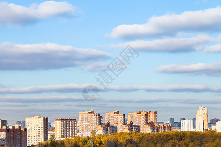 在阳光明媚的秋天蓝在现代公寓楼和黄树林上云笼罩图片
